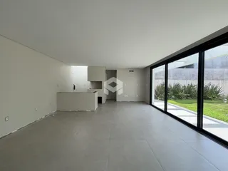 Ambiente interno amplo com piso de concreto e grandes janelas.