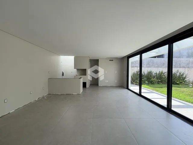 Ambiente interno amplo com piso de concreto e grandes janelas.
