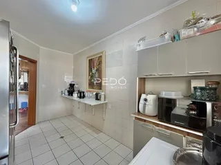 Cozinha com piso de cerâmica e armários brancos em imóvel no Brasil.