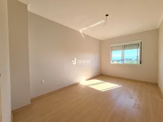 Sala de estar com piso de madeira clara e parede branca.