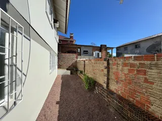 Vista externa da parede de um imóvel em Lajeado, Brasil, com muro de tijolos aparentes.