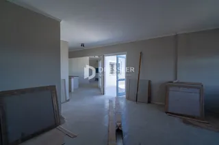Interior de uma sala em construção com paredes e piso expostos.