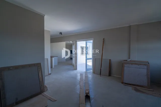 Interior de uma sala em construção com paredes e piso expostos.
