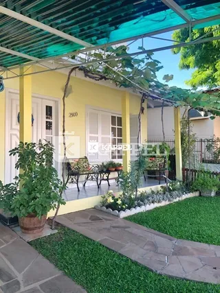 Jardim externo com gramado e plantas em uma área de lazer coberta por uma estrutura de pergolado.