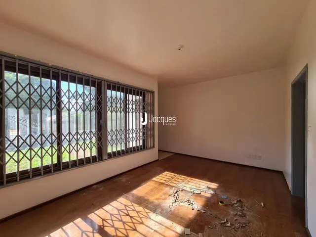 Interior de uma sala com piso de madeira e grande janela.