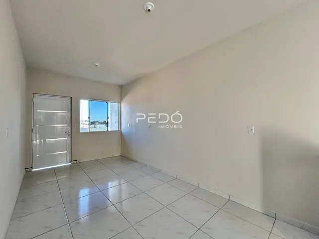 Ambiente interno de uma sala com piso de cerâmica e paredes brancas.
