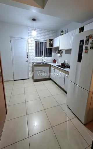 Vista da cozinha com revestimento de tijolos brancos e piso cerâmico claro.