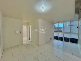 Ambiente interno de uma sala ampla com piso de cerâmica e portas de vidro.