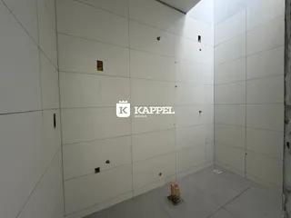 Foto de um corredor interno com paredes brancas e piso de concreto.