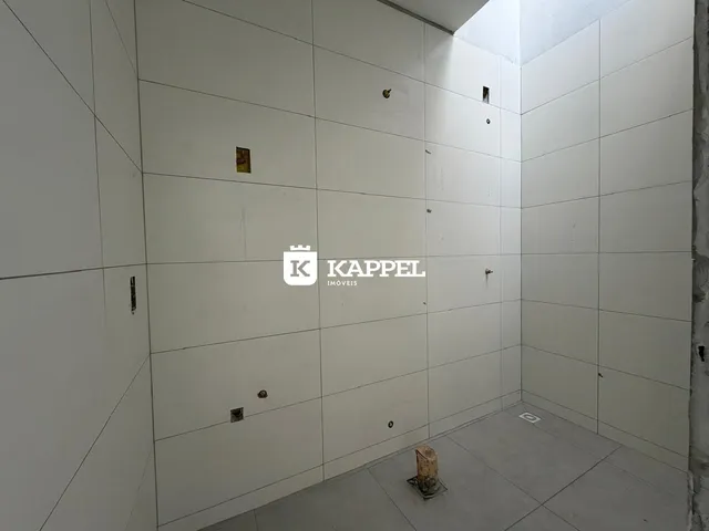 Foto de um corredor interno com paredes brancas e piso de concreto.