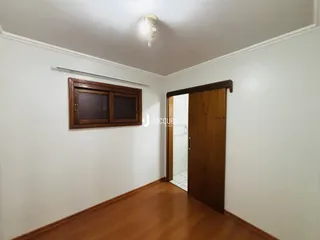 Uma vista de um corredor com piso de madeira e armário em uma sala.
