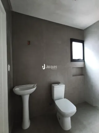 Foto de um banheiro com pia e vaso sanitário em uma parede cinza.