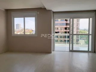 Interior de uma sala com piso de madeira e grandes janelas com vista para o exterior.