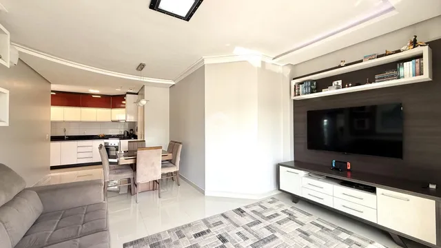 Sala de estar com cozinha e área de jantar em um apartamento.