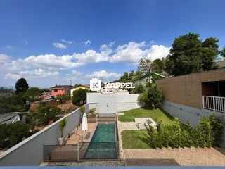 Foto da área externa com piscina e jardim de uma residência.