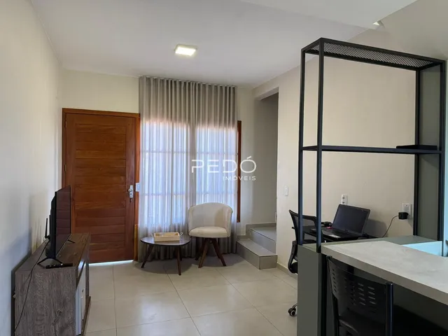 Sala de estar com porta de madeira e janela com cortinas claras.