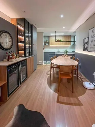Ambiente de sala de jantar e cozinha com piso de madeira clara.