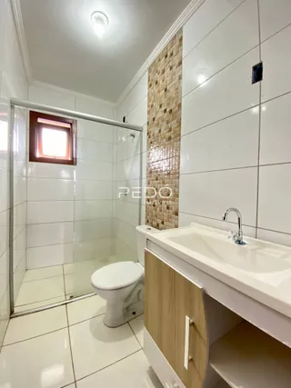 Banheiro com revestimento cerâmico e bancada de madeira clara.