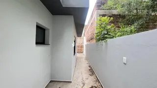 Vista de um corredor lateral com paredes brancas e vegetação ao fundo.