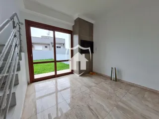 Ambiente interno com piso de cerâmica e porta de vidro que dá acesso ao jardim.