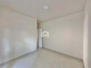 Vista de um corredor interno com paredes brancas e piso claro.