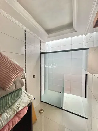 Interior de um banheiro com box de vidro transparente.