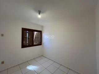 Vista interna de um cômodo com piso de cerâmica e janela de madeira.