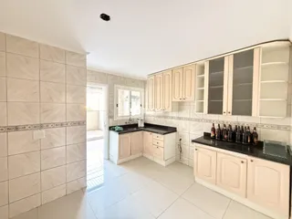 Foto de uma cozinha com armários brancos e piso claro em um imóvel no Brasil.
