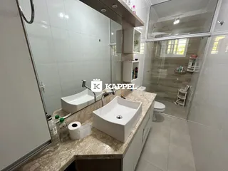 Banheiro moderno com bancada de mármore e pias brancas.