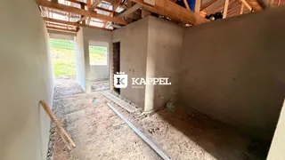 Foto de um ambiente interno em construção com estrutura de teto e paredes expostas.