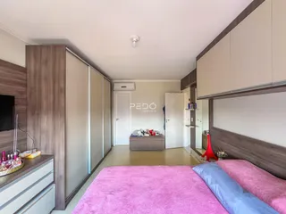Quarto com armários em madeira e cama rosa.