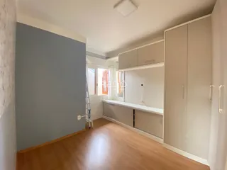 Um cômodo interno com paredes cinzas e piso de madeira clara.