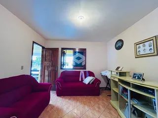 Sala de estar com sofá vermelho e piso de cerâmica em um imóvel no Brasil.