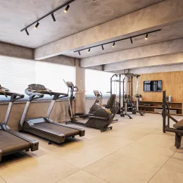 Foto de uma área de ginástica interna com esteiras e equipamentos de musculação.
