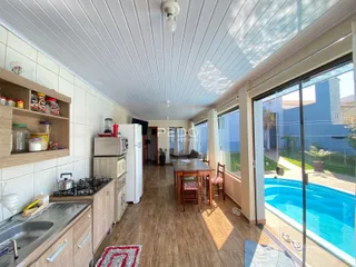 Sala de estar e cozinha de uma residência em Lajeado, Brasil, com vista para a piscina externa.