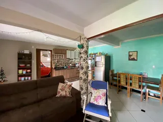 Sala de estar com sofá e cozinha visíveis em um imóvel no Brasil.