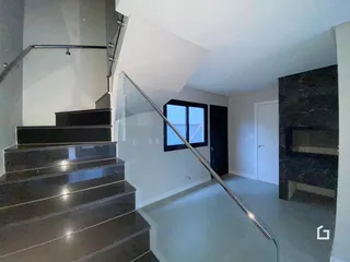 Vista interna de uma sala com escadaria e parede de destaque.
