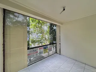 Vista da sala com grande janela de vidro para a vegetação externa.