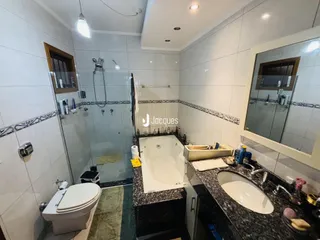 Banheiro com box de vidro e banheira em Lajeado.