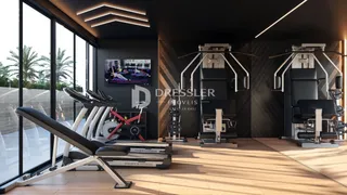 Interior de uma sala de ginástica com piso de madeira e grandes janelas.