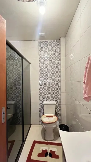 Foto interna de um banheiro com revestimento de azulejos e vaso sanitário.