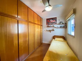 Quarto com armário de madeira e cama em um imóvel no Brasil.