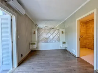 Sala de estar com piso de madeira e parede decorativa branca.