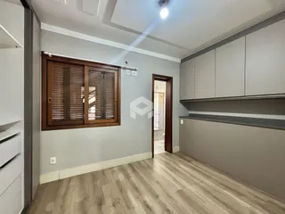 Interior de uma sala com piso de madeira clara e armários modernos.