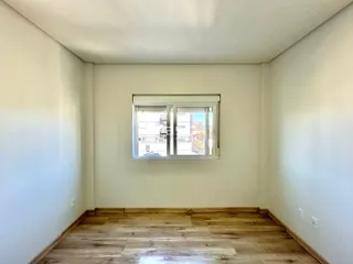 Uma sala de estar com piso de madeira clara e janela.