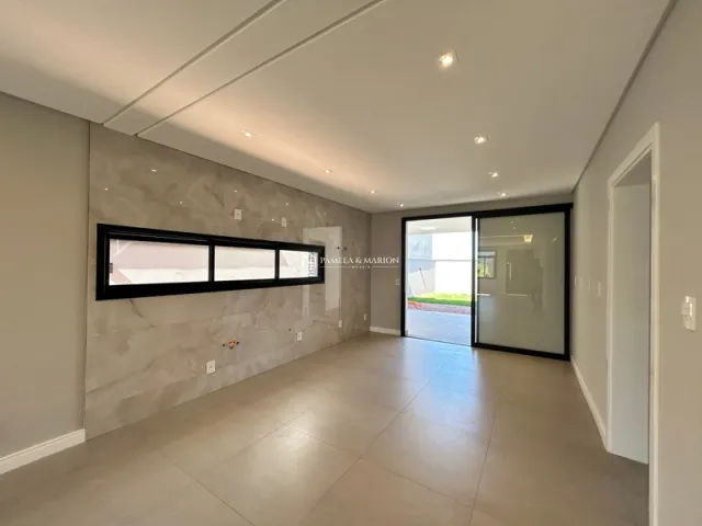 Foto interna de uma sala com piso claro e grandes portas de vidro.