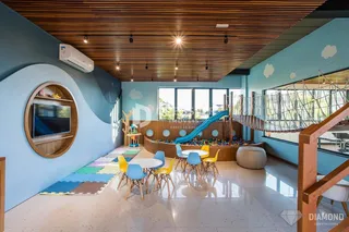 Sala de estar com teto de madeira e área de lazer com escorrega.