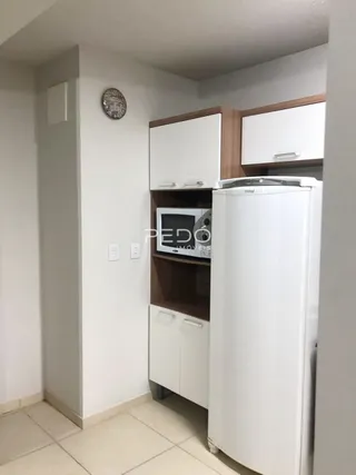 Uma cozinha com armários brancos e geladeira branca.