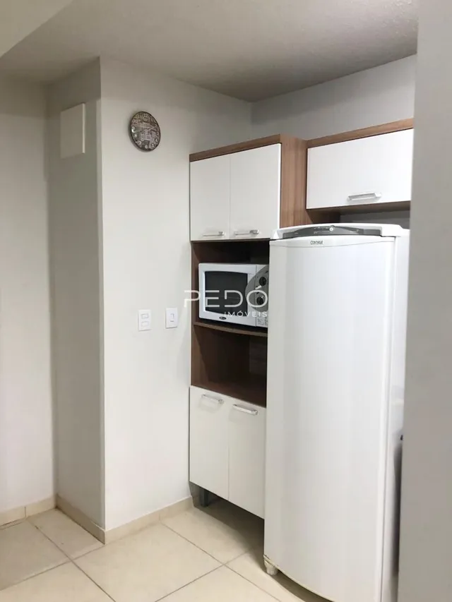 Uma cozinha com armários brancos e geladeira branca.