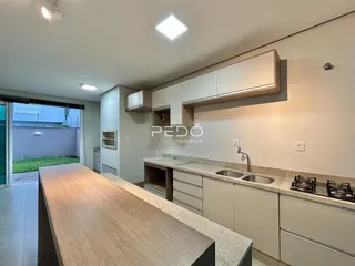 Uma cozinha moderna com armários claros e uma ilha grande é mostrada.